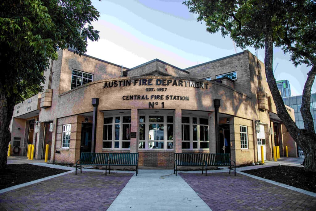 An exterior view of Austin Fire Department Central Fire Station No. 1, surrounded by trees and a brick walkway.