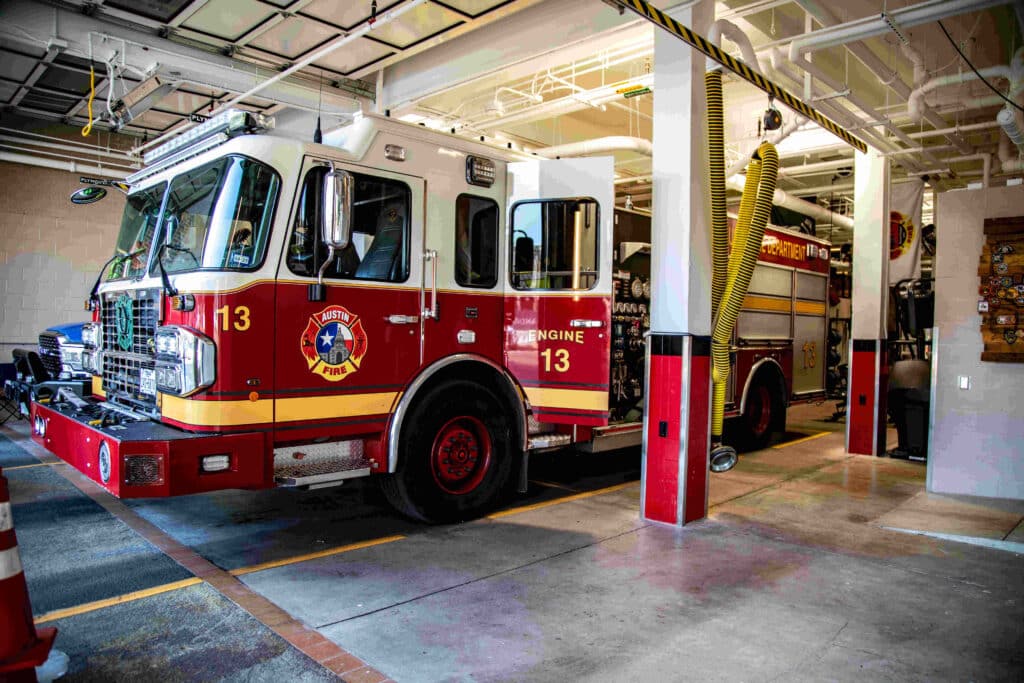 A red and white Austin Fire Department truck parked in a fire station garage.