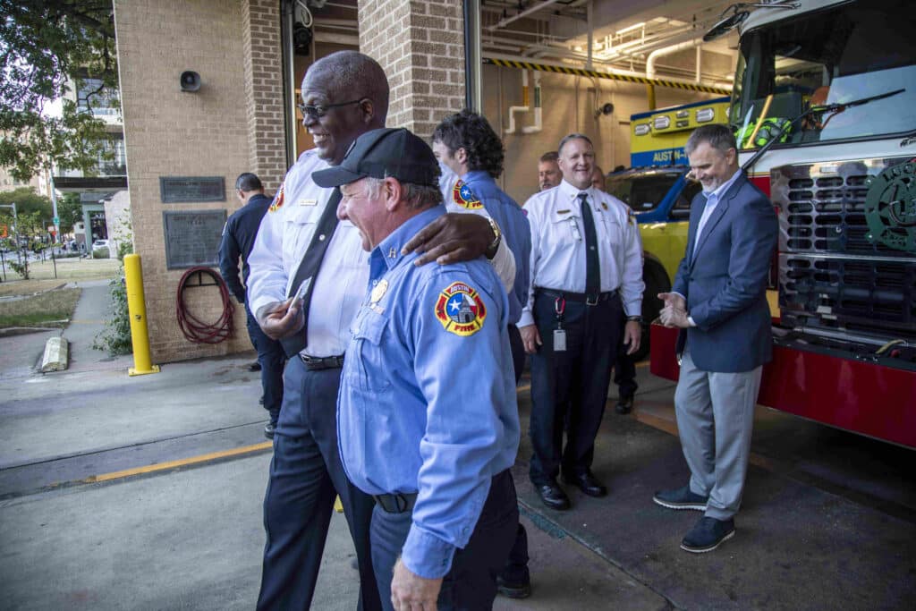 Firefighters smiling together at the entrance of a station.