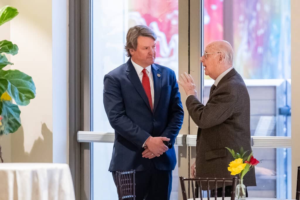 Two men talking in a formal setting.