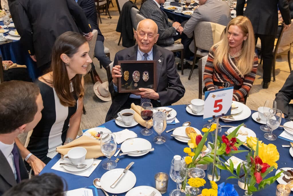 Man showing badge plaque at dinner event.