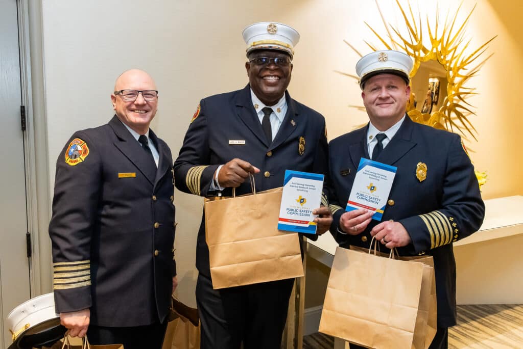 Firefighters at safety commission event holding bags and booklets.