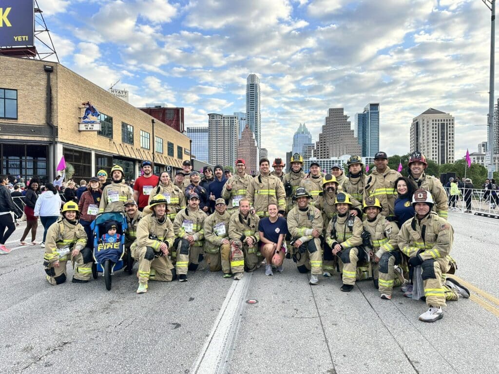 Group of firefighters pose on urban street.