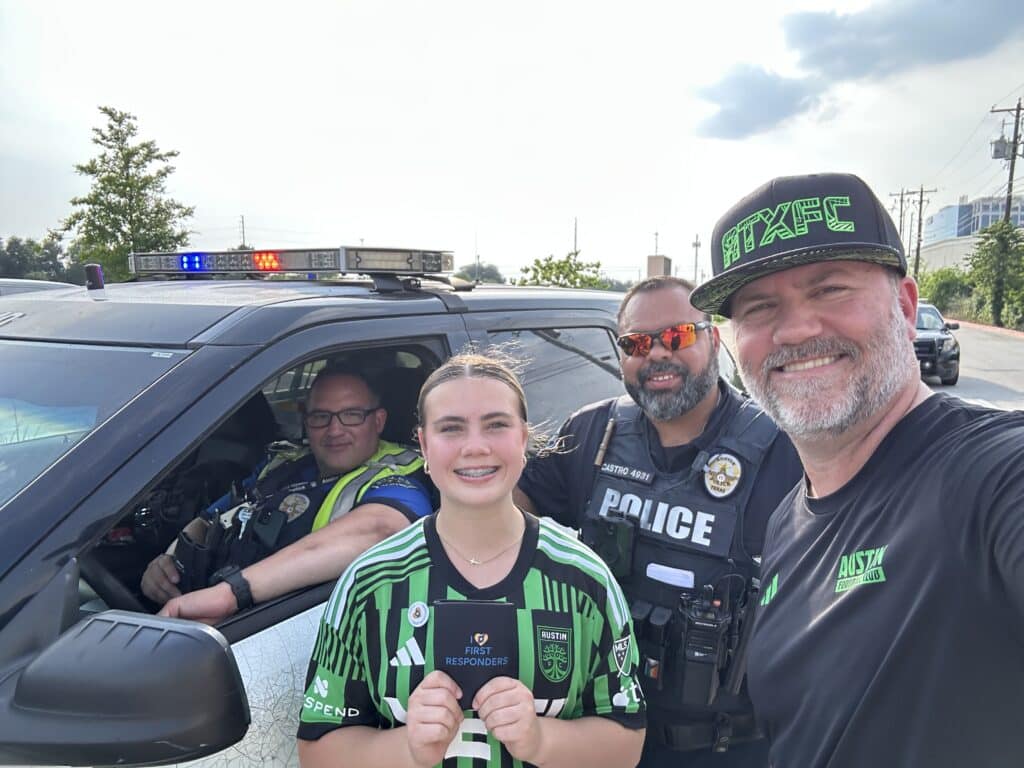 Group smiling with police officer and patrol car.