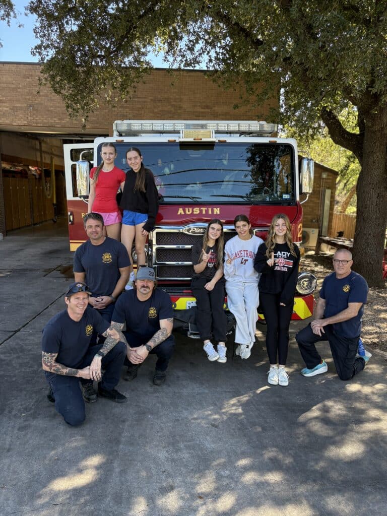 Firefighters and teens posing before Austin fire truck