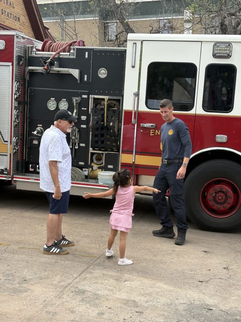 Firefighter talking with child beside fire truck