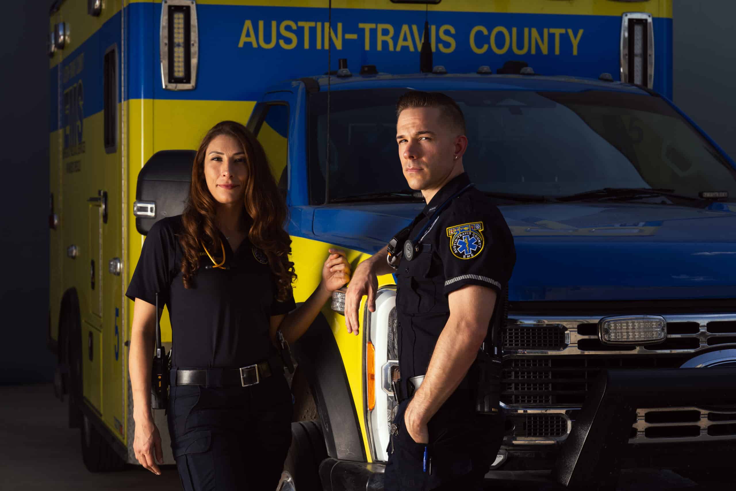 Two EMS workers beside Austin-Travis County ambulance