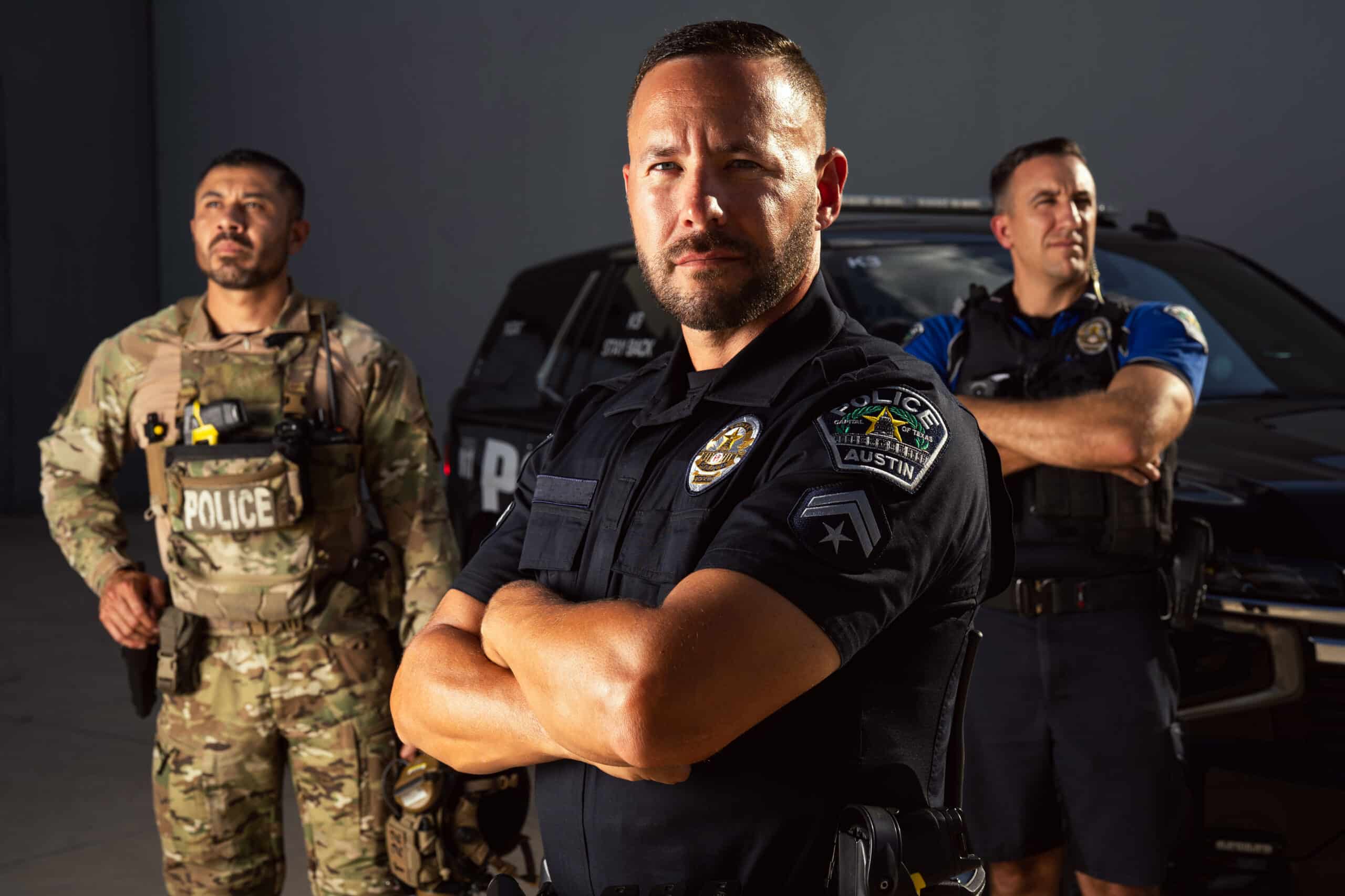 Three police officers standing before patrol SUV